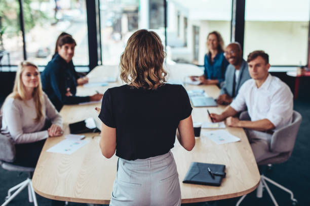 Woman standing in front of boardroom of employees.